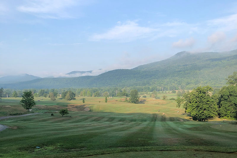 Golf course in the foreground with majestic Adirondack cloud topped mountains in the background